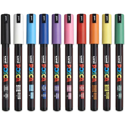 A collection of Posca water-based paint markers with fine tips, displayed in a row with various colors.